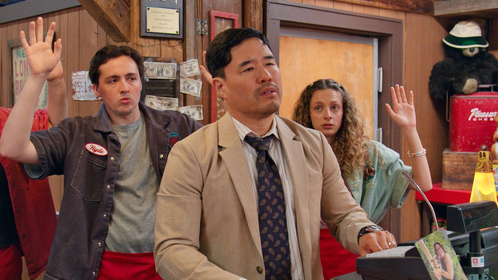 Randall Park e integrantes do elenco de Minimum Wage dentro da pizzaria Slice Club